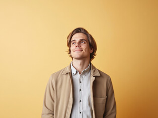 Fototapeta premium Portrait of a smiling man in her 20s standing on a solid color background, luminous, casual cloth