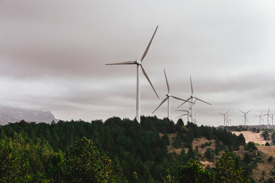 Wind turbines standing tall against a dramatic cloudy sky, emphasizing the contrast between modern technology and the natural elements in an evocative landscape.