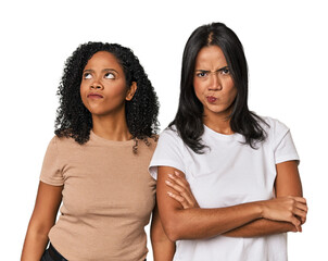 Young Latin friends in studio frowning face in displeasure, keeps arms folded.