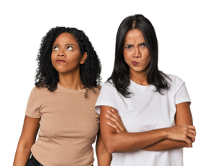 Young Latin friends in studio frowning face in displeasure, keeps arms folded.