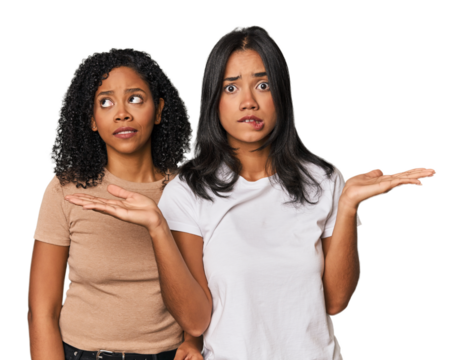 Young Latin friends in studio confused and doubtful shrugging shoulders to hold a copy space.