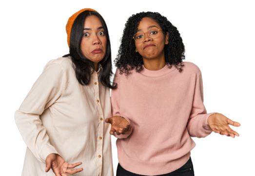 Young Latin friends together in studio doubting and shrugging shoulders in questioning gesture.