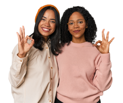 Young Latin friends together in studio cheerful and confident showing ok gesture.