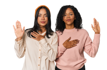 Young Latin friends together in studio taking an oath, putting hand on chest.