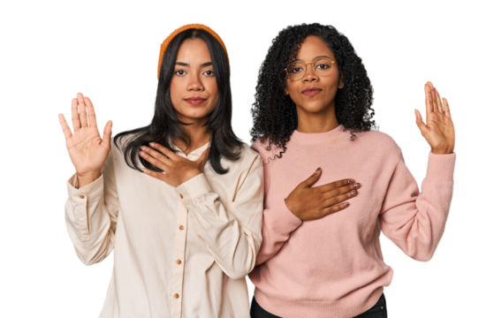 Young Latin friends together in studio taking an oath, putting hand on chest.