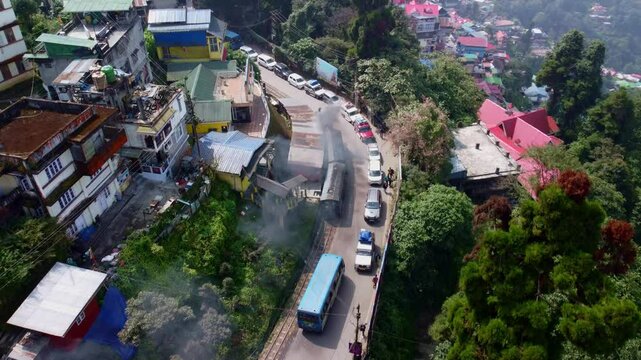 Darjeeling Himalayan Railway steam engine toy train through city neighbourhood, West Bengal, Drone shot