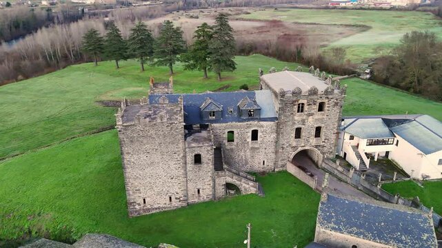 Aerial shot of Arnedo Castle, a historic stone fortress with towers and archways, surrounded by green fields and trees in Valdeorras.