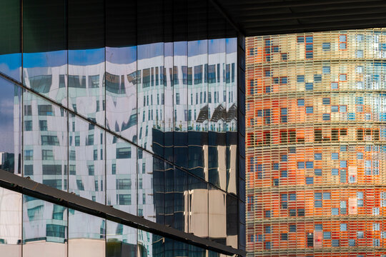 The image illustrates a dynamic cityscape showing modern facades reflecting each other, creating intriguing patterns and visual depth while emphasizing urban life.