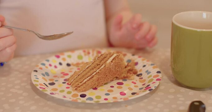 Family with children. Hand with delicious cake at a joyful gathering, family members are happily enjoying each others company around a table, kids eating cack.