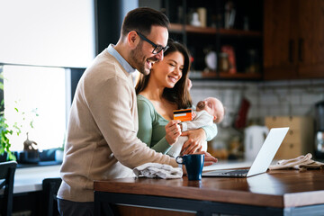 Cheerful young family with a baby child enjoying online purchasing on the internet at home