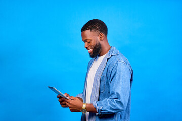 Smiling young man using digital tablet on blue background