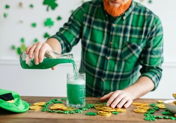 Fototapeta premium Man pouring green beer on St. Patrick's Day with gold coins and shamrocks