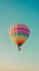Fototapeta premium A colorful hot air balloon floats in the clear blue sky, seen from below with no clouds in sight
