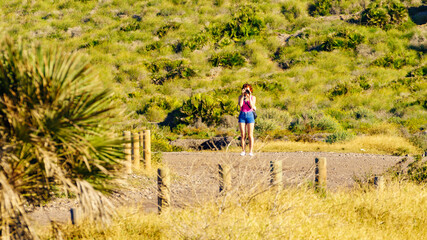 Woman walk on spanish coast, take photo with camera