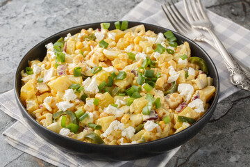 Mexican Corn Potato Salad made with corn kernels in a creamy mixture of mayonnaise, sour cream, cheese closeup on the plate on the table. Horizontal