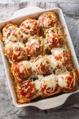 Meatball Stuffed Garlic Bread Sliders topped with cheese closeup on the baking dish on the table....