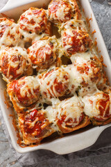 Garlic Bread Meatball Bombs are dinner rolls stuffed with a meatball and sauce, then topped with cheese closeup on the baking dish on the table. Vertical top view from above