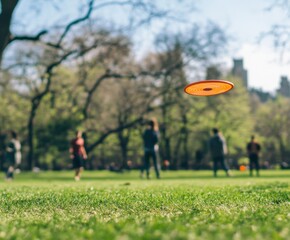 Frisbee flying over a green field with people enjoying a sunny day in the park