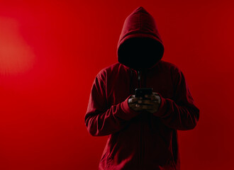 Hacker using smartphone over red background. Concept of data thief, internet fraud, darknet and...