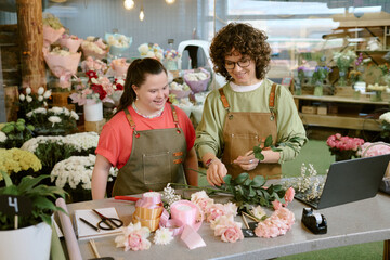 High angle shot of Caucasian florists making adorable bouquet made of pastel pink roses together in...