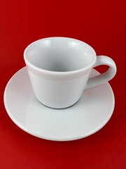 White cup and saucer for drinking isolated on red background