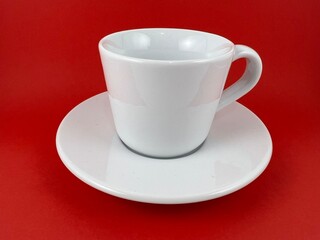White cup and saucer for drinking isolated on red background