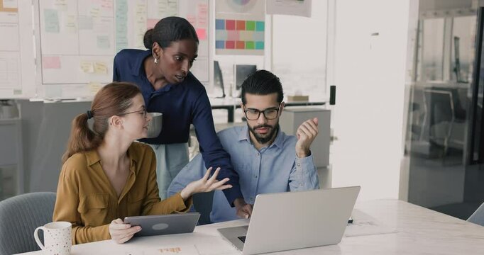 African mentor explains task details, work-related matters to team members during group briefing gathered in office, engaged in collaborative meeting, teamwork productive workflow using laptop and pad - Powered by Adobe