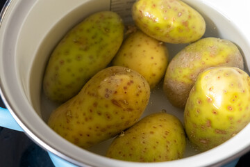 Boiling fresh unpeeled potatoes in a pot on the stove for a hearty meal preparation