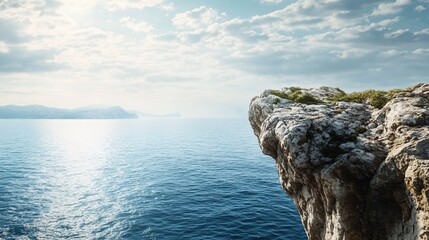 Rocky cliff overlooking the endless blue sea under a cloudy sky