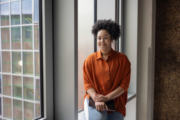 Portrait of an African American businesswoman holding a digital tablet sitting by a modern office window