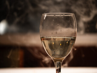 Glass of sparkling white wine with smokey background