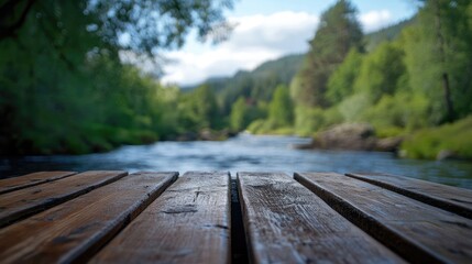 Fototapeta premium Wooden table in focus with serene blurred river landscape and lush greenery in background creating a tranquil outdoor setting