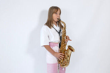 Girl playing, practicing the saxophone, playing a melody on a musical instrument, standing against...