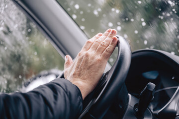 Honking car horn, male hand on a car steering wheel on cold winter day