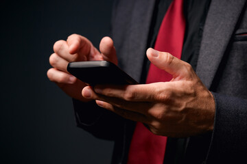E-commerce concept, mobile banking or electronic business, businessman using smartphone in dark office, low key