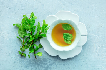 Mint tea. A cup of peppermint tea with fresh mint leaves, overhead flat lay shot on a blue background