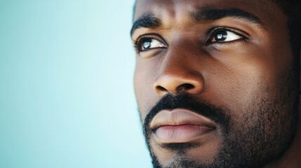 Obraz premium Close up portrait of a thoughtful African American man with a focused expression against a soft pastel backdrop