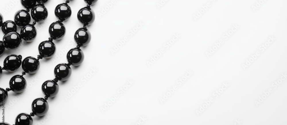 Poster elegant black smooth beads arranged on a white background with ample blank space for text or design 