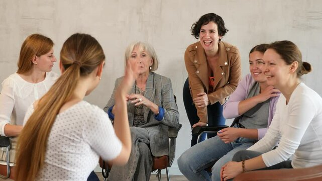 Friendly mixed age group of positive women of different nationalities participating together educational course discussing with interest study topics while sitting on chairs in circle in classroom
