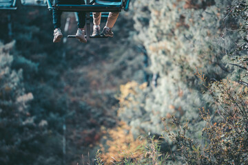Suspended high above Yunnan, China's Dali landscape, three pairs of legs dangle from a cable car, offering a breathtaking view of the valley below.