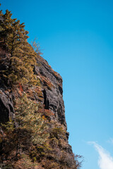 A dramatic cliff face in Yunnan, China, rises sharply against a vibrant blue sky.  The rugged rock is sparsely vegetated, showcasing the region's unique Dali landscape.