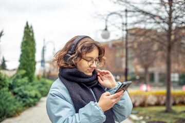 A teenage girl uses a phone in the city. Girl in the city. Technology concept.