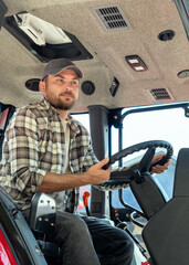 Obraz premium Portrait of a Caucasian farmer driving a red tractor in the countryside.