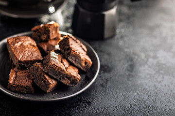 Homemade chocolate brownies on plate on black table.
