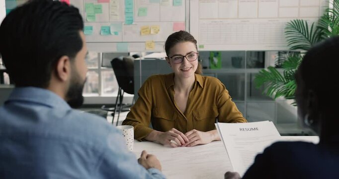 Hiring, new job opportunities. Young 30s attractive applicant answers questions asked by two multiethnic recruiting managers holding curriculum vitae, interviewing vacancy candidate during interview