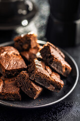 Homemade chocolate brownies on plate on black table.