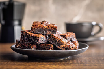 Homemade chocolate brownies on plate on wooden table.