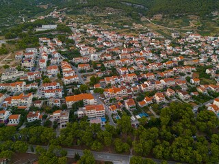 Aerial view of a small town with red-roofed houses surrounded by lush greenery. Bol, Brac Island