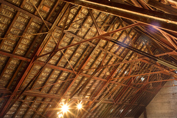 Interior view of a rustic ceiling with wooden beams and metal braces, illuminated by warm lights, Berlin, Germany