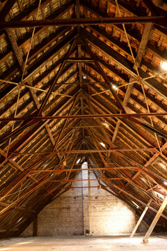 Wooden beams form a complex triangular structure in the attic of a historic building illuminated by natural light, Berlin, Germany